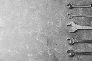 Photo of New wrenches on grey background, top view with space for text. Plumber tools