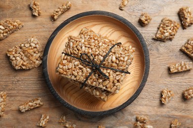 Photo of Delicious sweet kozinaki bars on wooden table, flat lay