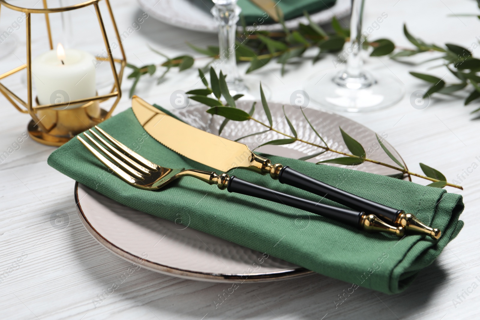 Photo of Stylish setting with cutlery and eucalyptus leaves on white wooden table