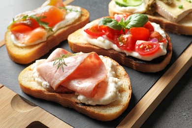 Board with different tasty bruschettas on table, closeup