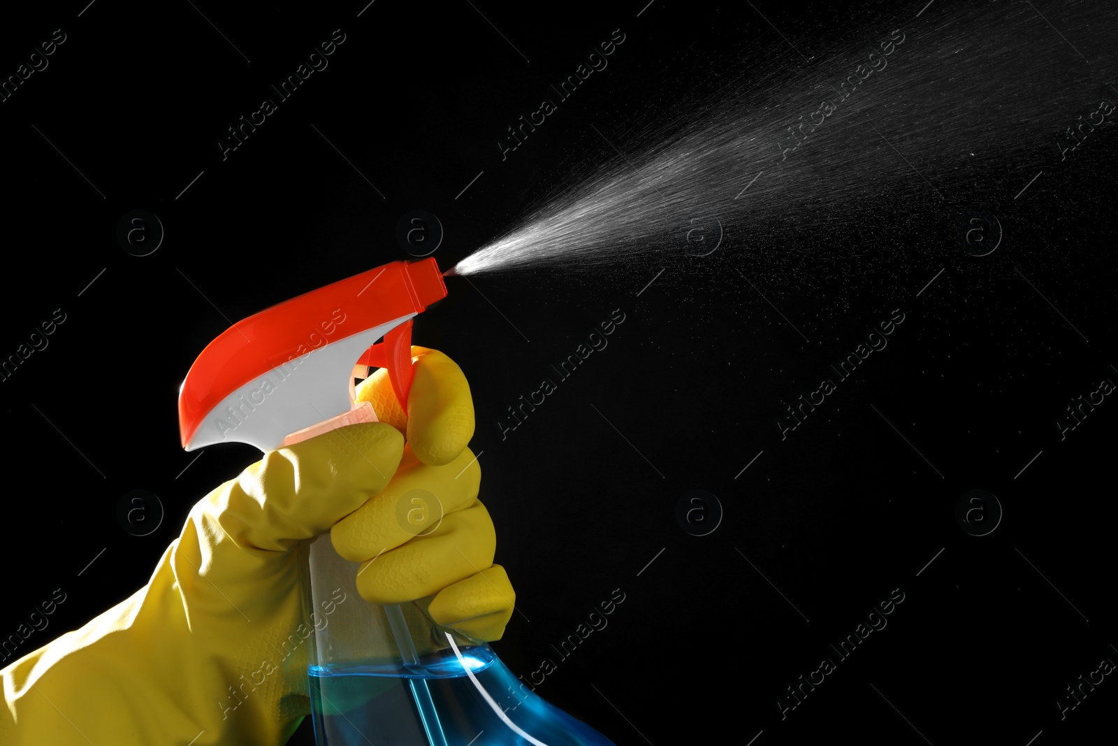 Photo of Woman spraying liquid from bottle on black background, closeup