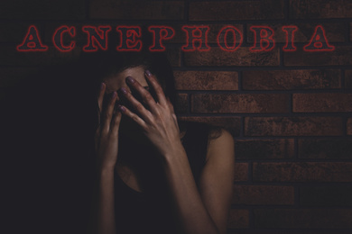 Image of Acnephobia concept. Scared woman hiding face in darkness