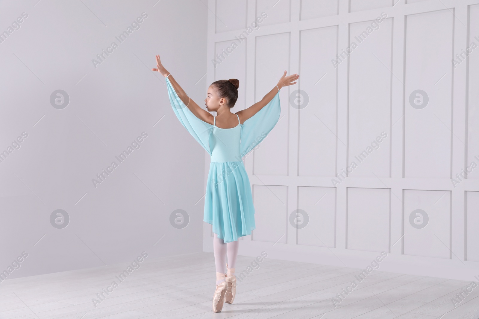 Photo of Beautifully dressed little ballerina dancing in studio