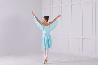 Photo of Beautifully dressed little ballerina dancing in studio