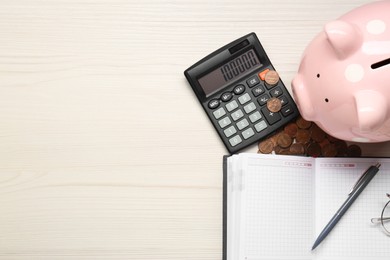 Calculator, piggy bank, notebook and coins on white wooden table, flat lay. Space for text