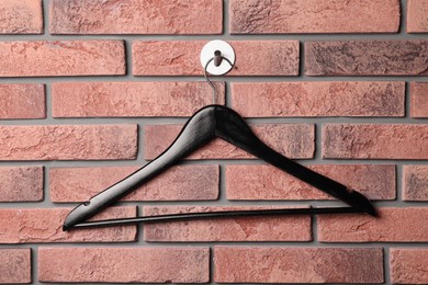 Photo of Black clothes hanger on red brick wall
