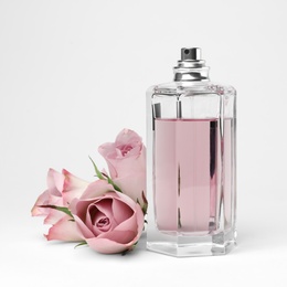 Photo of Transparent bottle of perfume with beautiful roses on white background