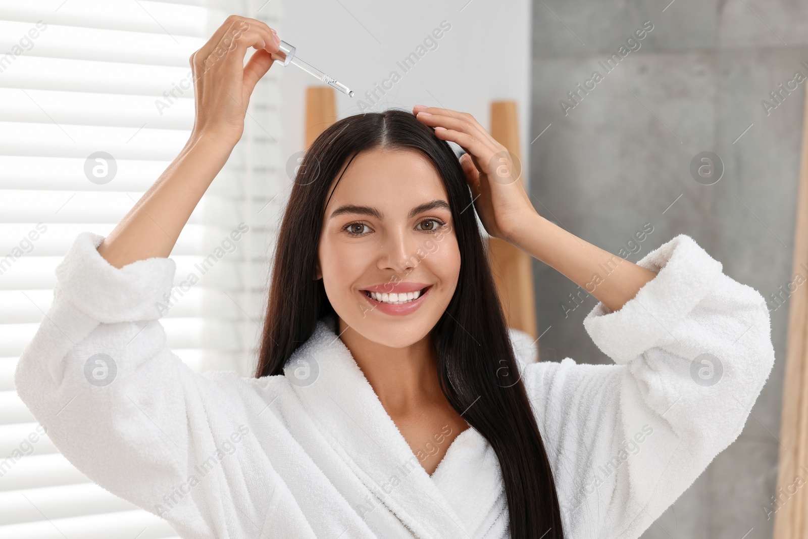 Photo of Beautiful woman applying hair serum indoors. Cosmetic product