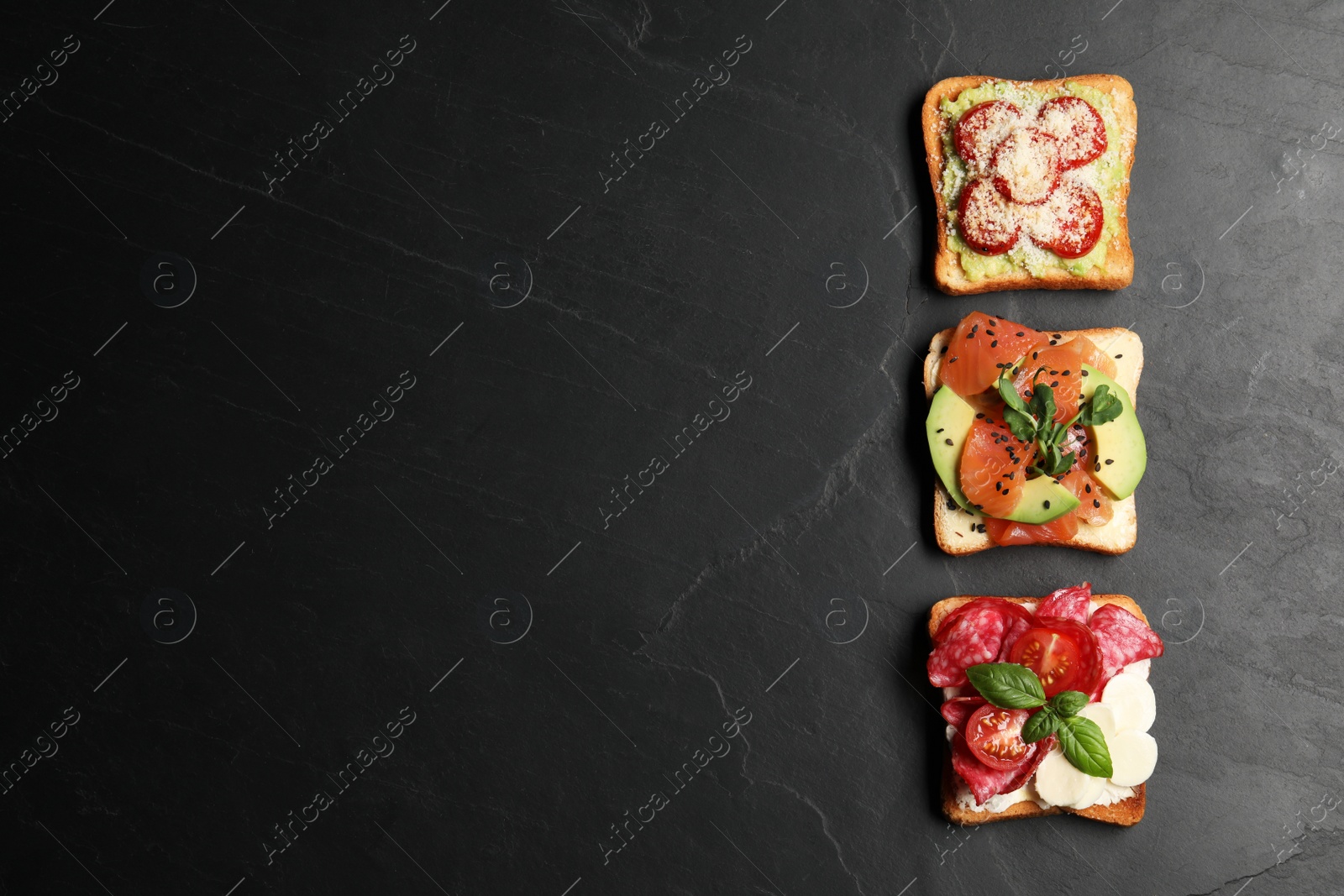 Photo of Tasty toasts with different toppings on black table, flat lay. Space for text