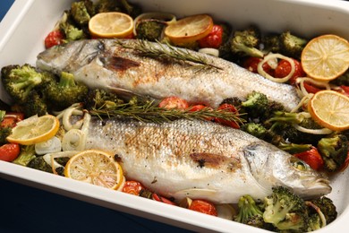 Photo of Delicious fish with vegetables and lemon in baking dish on table, closeup