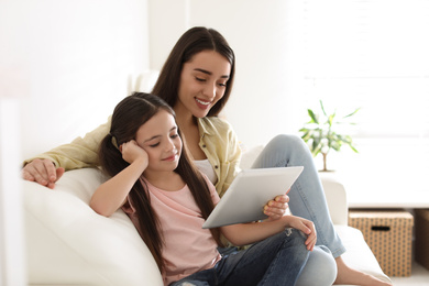 Mother and daughter reading E-book together at home