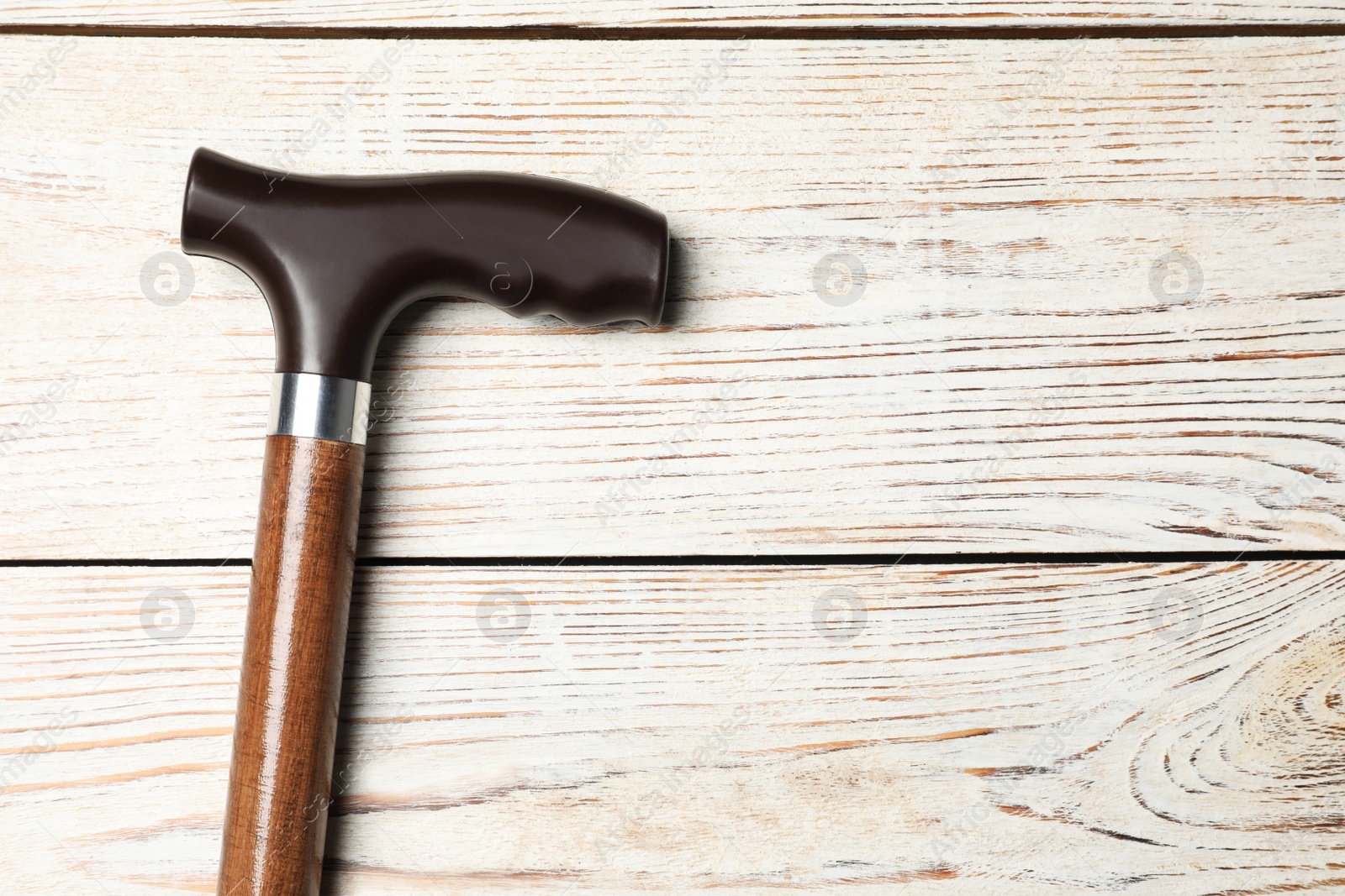 Photo of Walking cane on white wooden background, top view. Space for text