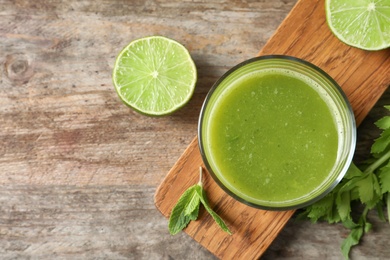 Glass with delicious detox juice and ingredients on wooden background, top view