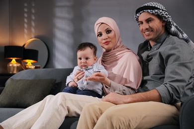 Photo of Happy Muslim family with little son in living room