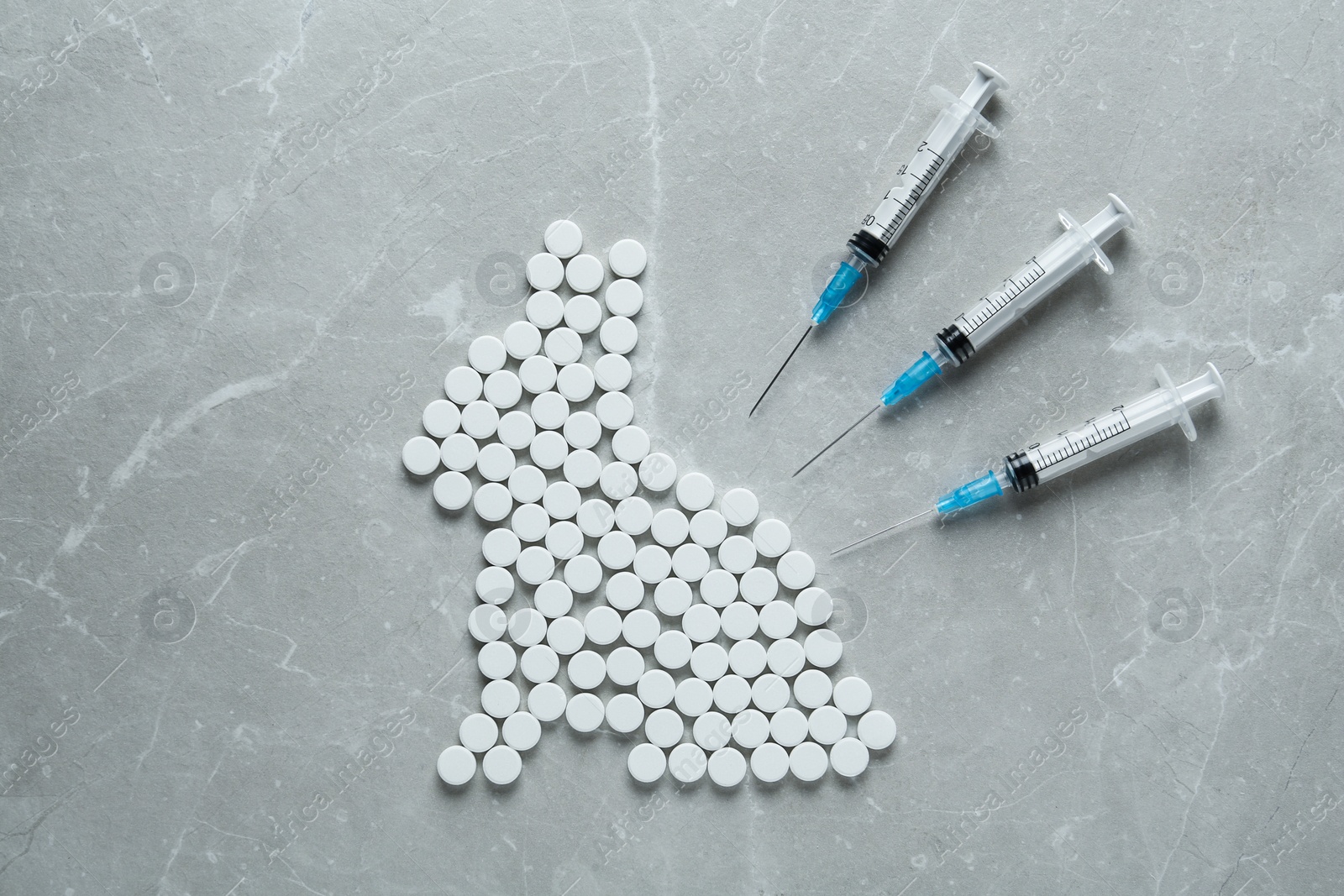 Photo of Rabbit figure of pills and syringes on light marble table, flat lay. Stop animal tests