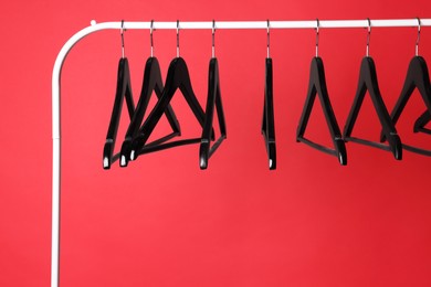 Photo of Black clothes hangers on metal rack against color background