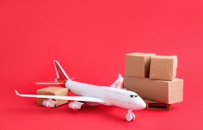 Photo of Airplane model and carton boxes on red background. Courier service