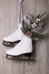 Pair of ice skates with Christmas decor hanging on wooden wall