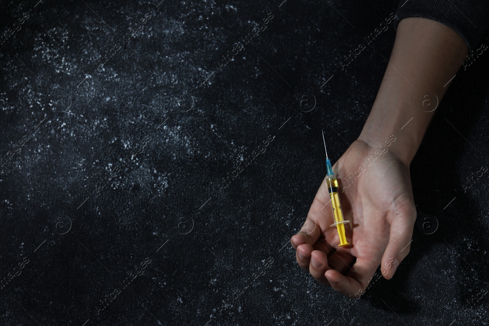 Photo of Drug addiction. Man with syringe on black textured table, top view and space for text