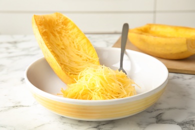 Photo of Cooked spaghetti squash and fork in dish on table