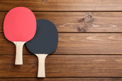 Ping pong rackets on wooden table, flat lay. Space for text