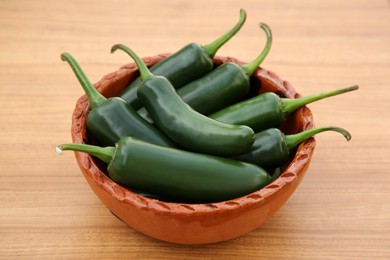 Photo of Bowl of fresh green jalapeno peppers on wooden table