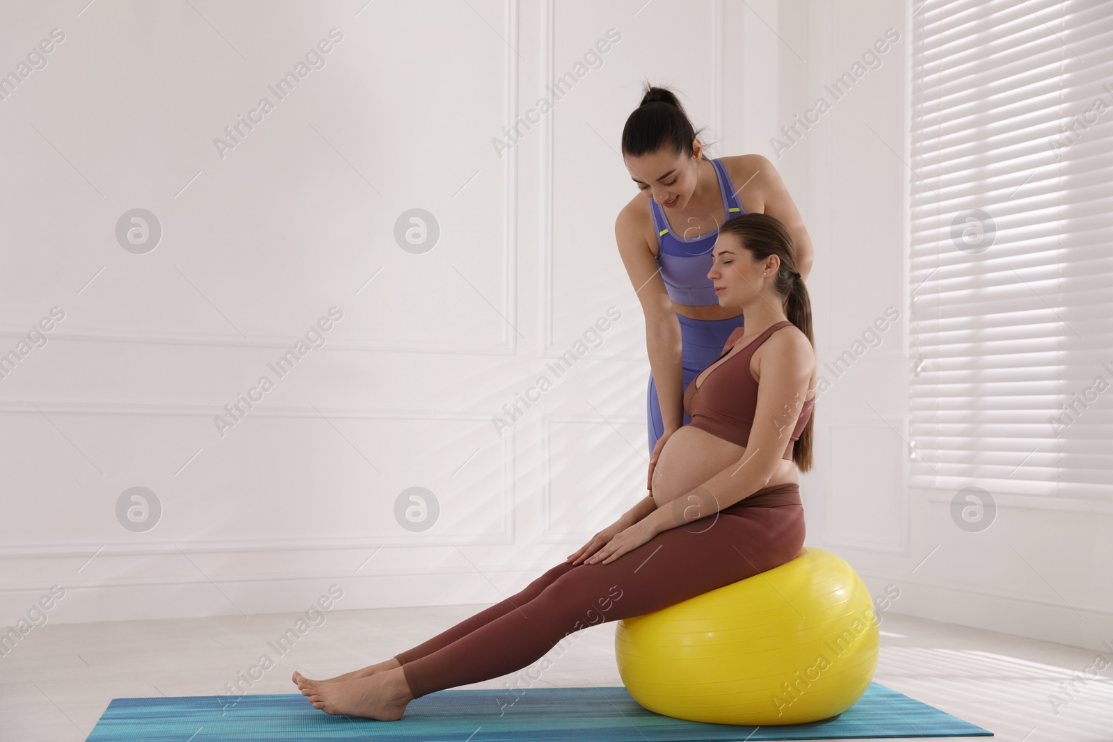 Photo of Trainer working with pregnant woman in gym. Preparation for child birth