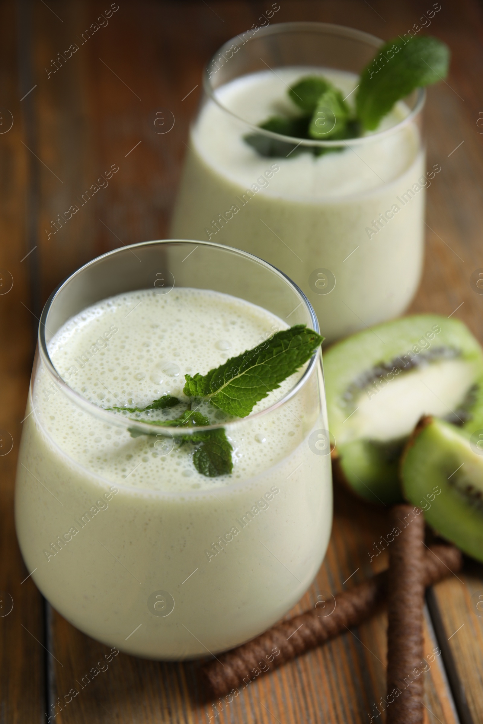 Photo of Tasty milk shake with kiwi on wooden table, closeup