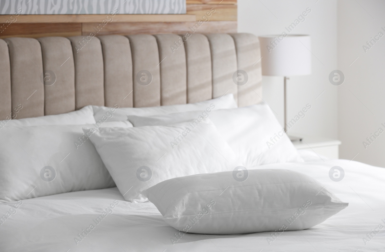 Photo of Bed with soft pillows in room. Modern interior