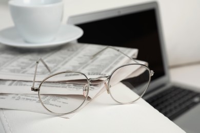 Photo of Newspapers, glasses and cup of drink on armrest indoors