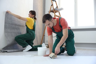 Photo of Workers hanging stylish gray wallpaper in room