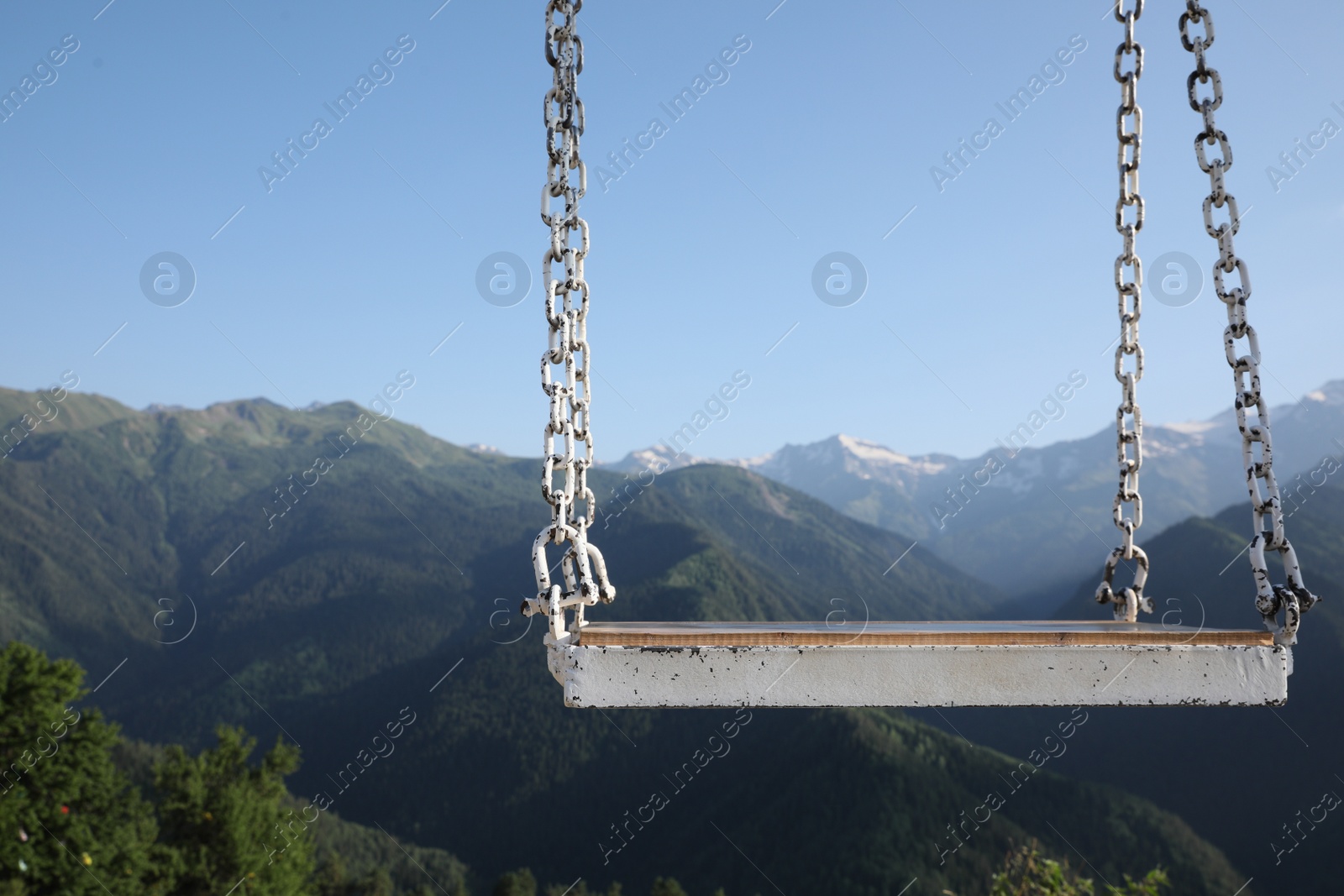 Photo of Outdoor metal swing in beautiful mountains on sunny day, space for text