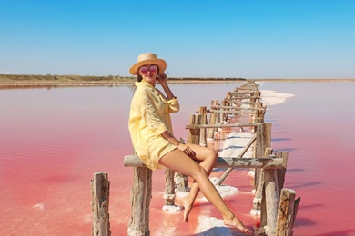 Photo of Beautiful woman with hat posing near pink lake on summer day