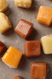 Photo of Different frozen fruit puree cubes on brown marble table, flat lay