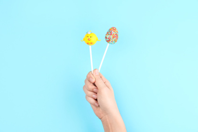 Woman with delicious cake pops on light blue background, closeup. Easter holiday