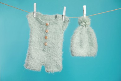 Photo of Knitted baby clothes drying on washing line against turquoise background