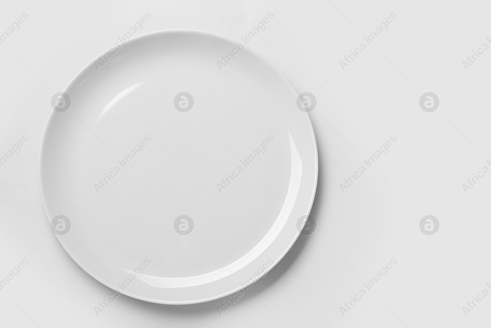 Photo of Empty ceramic plate on white background, top view. Space for text