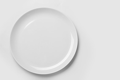 Photo of Empty ceramic plate on white background, top view. Space for text