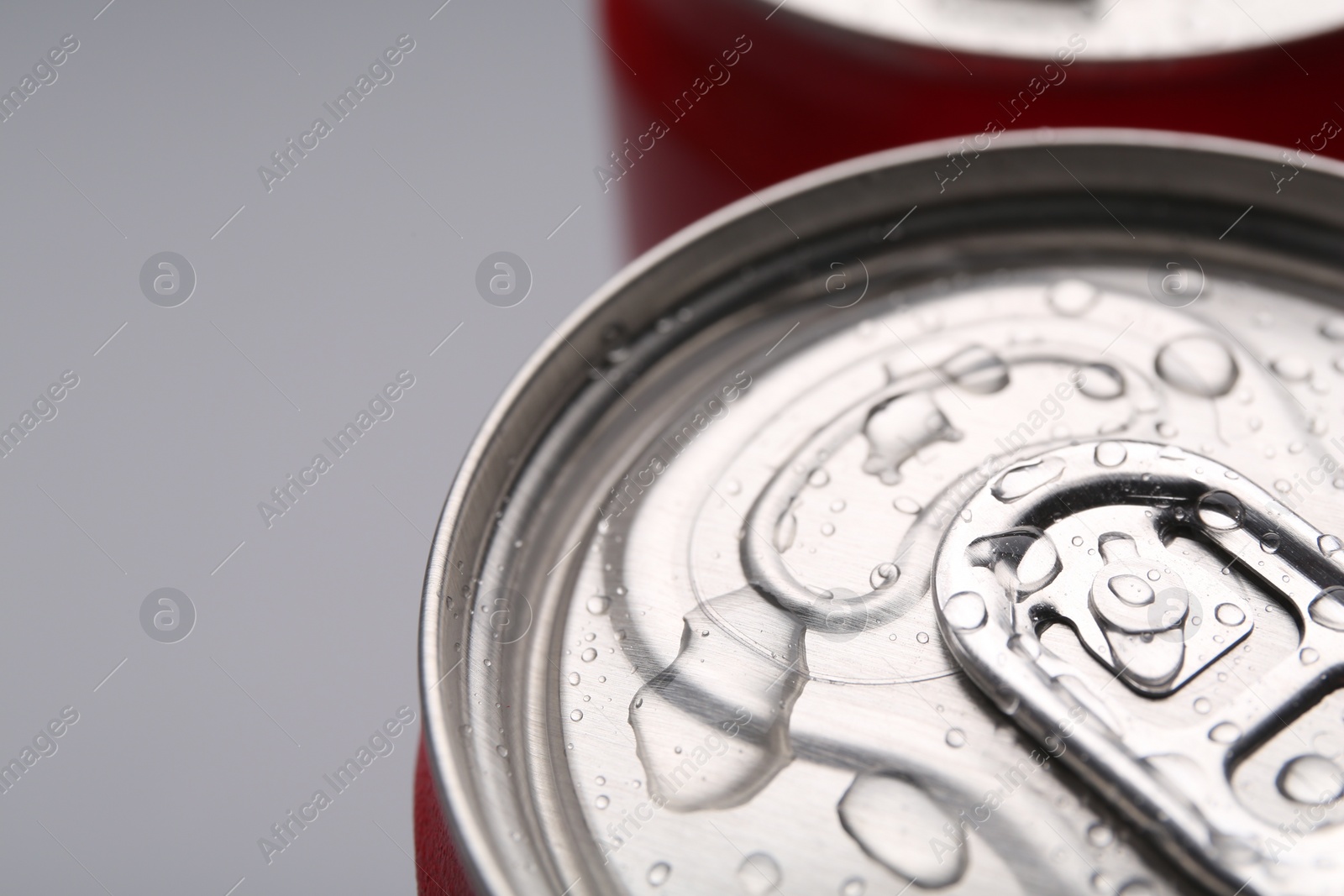 Photo of Energy drinks in wet cans on grey background, closeup. Space for text