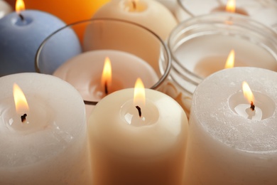 Photo of Burning wax candles of different shapes and colors, closeup