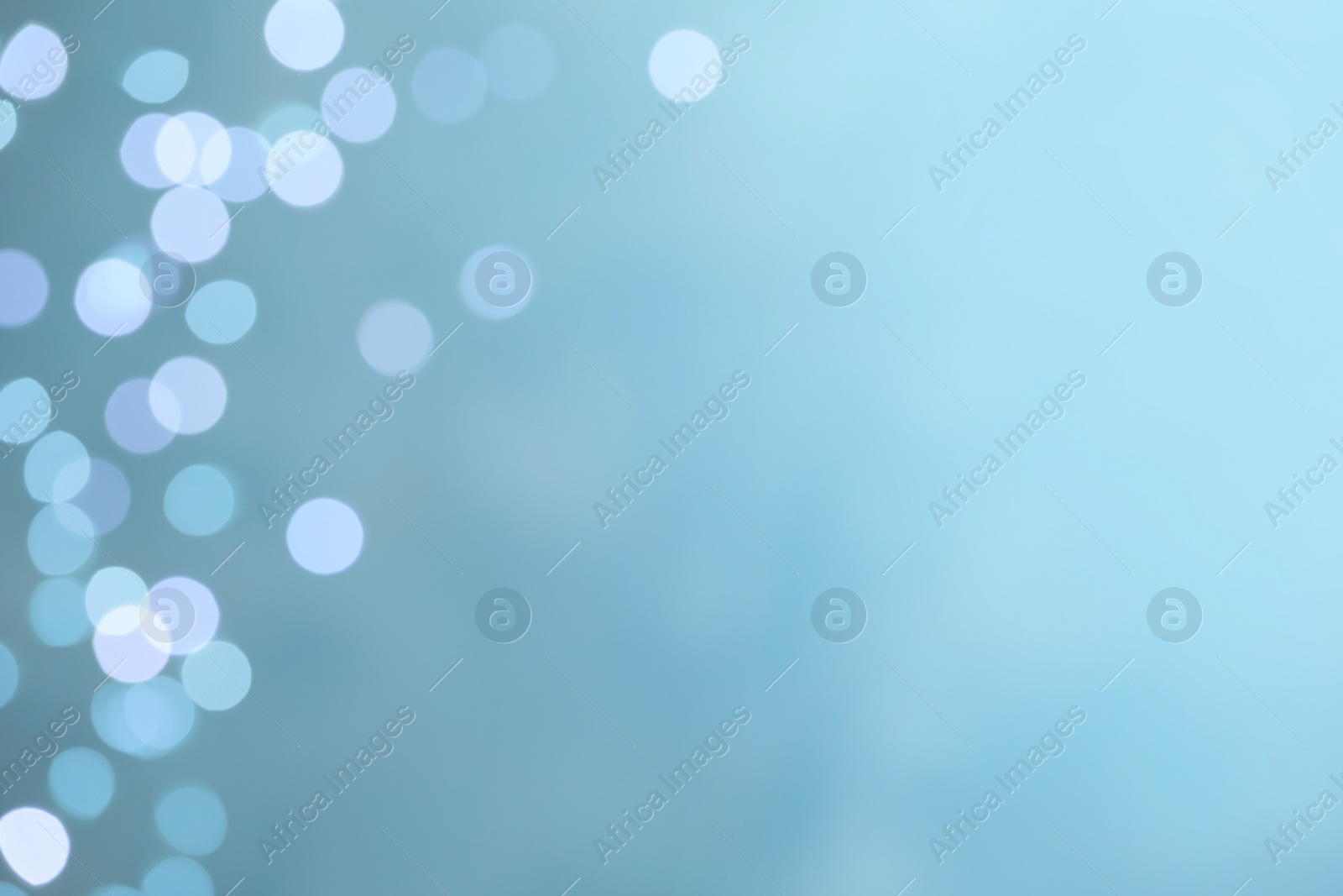 Photo of Blurred view of festive lights on light blue background, space for text. Bokeh effect