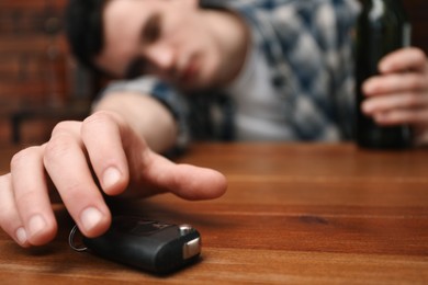 Drunk man reaching for car keys at table, selective focus. Don't drink and drive concept