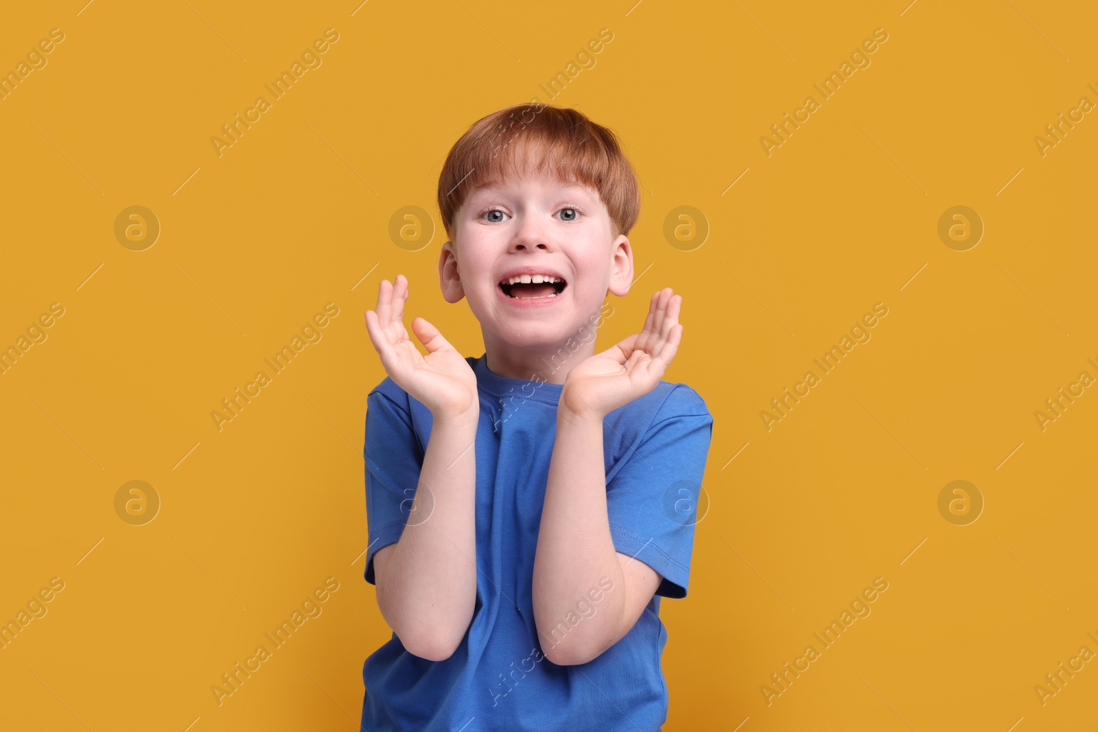 Photo of Portrait of surprised little boy on orange background