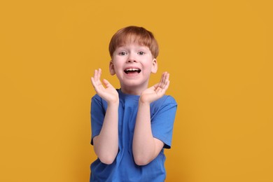 Portrait of surprised little boy on orange background