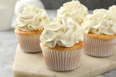 Photo of Tasty cupcakes with vanilla cream on grey table, closeup