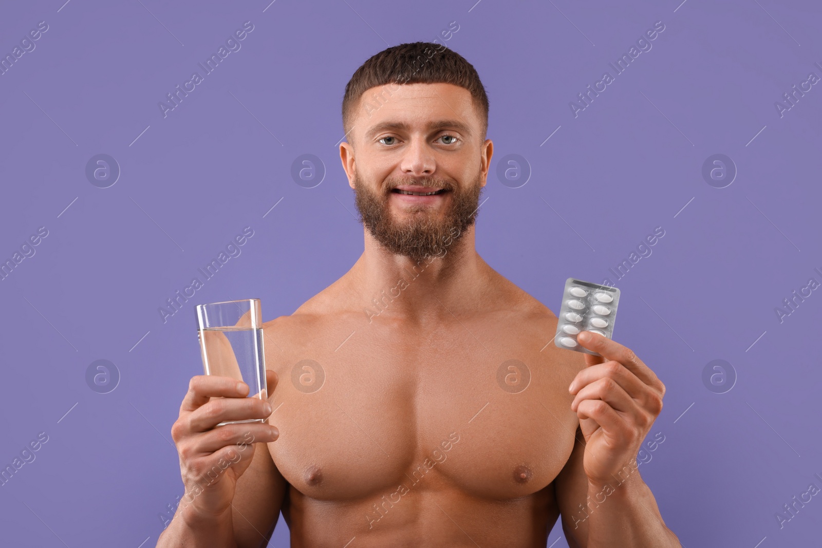 Photo of Athletic young man with pills and glass of water on purple background. Weight loss