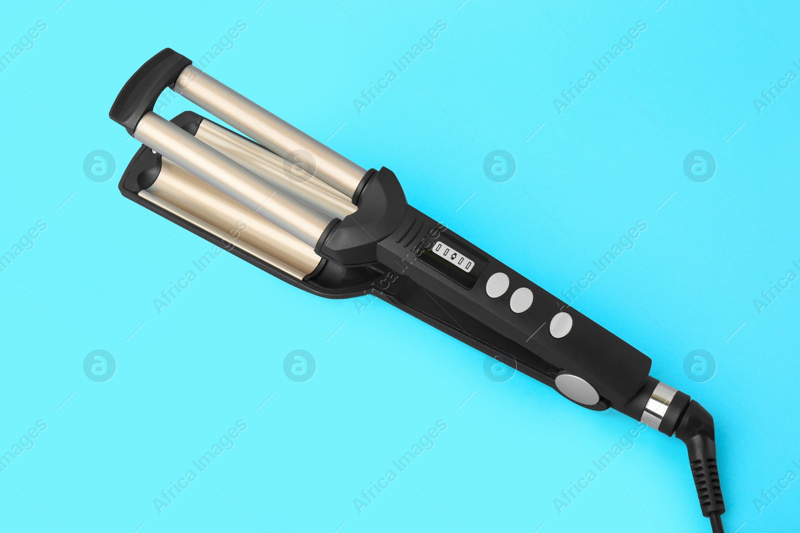 Photo of Modern triple curling iron on light blue background