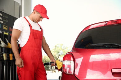Worker refueling car at modern gas station
