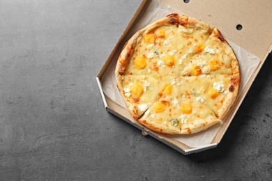 Cheese pizza in carton box on grey background, top view with space for text. Food delivery service