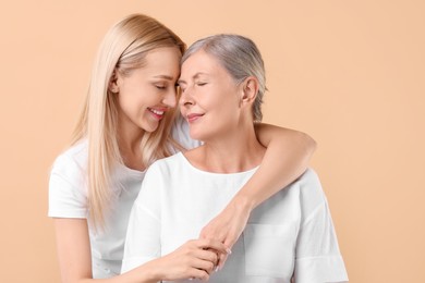 Photo of Family portrait of young woman and her mother on beige background